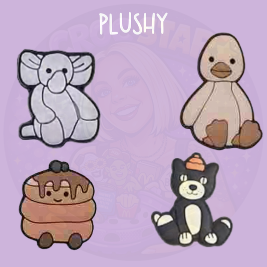 Set of four cute plush animal croc charms including elephant, duck, bear and dessert themed design on a purple background