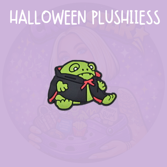Jellycat Halloween Croc charm featuring a cute green monster plush character wearing a black cape with red bow details
